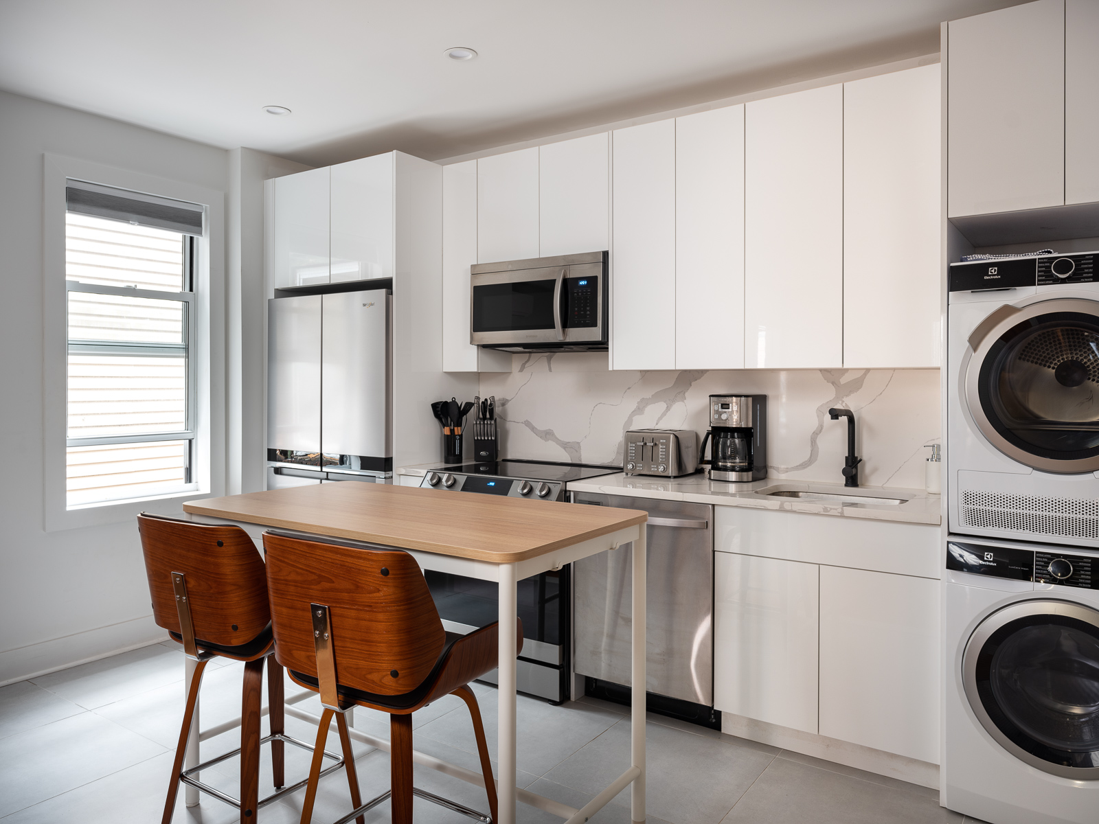 Bright white kitchen with walnut stools at the island
