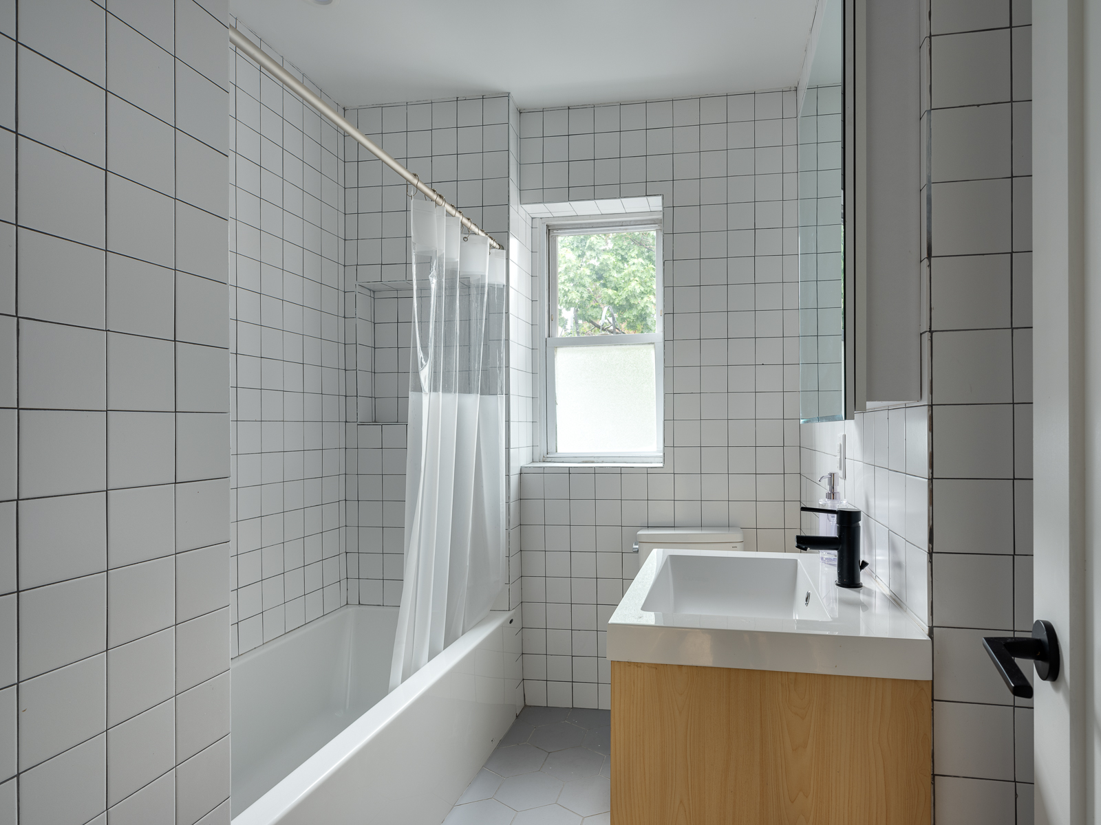 White tiled hall bathroom with soaking tub